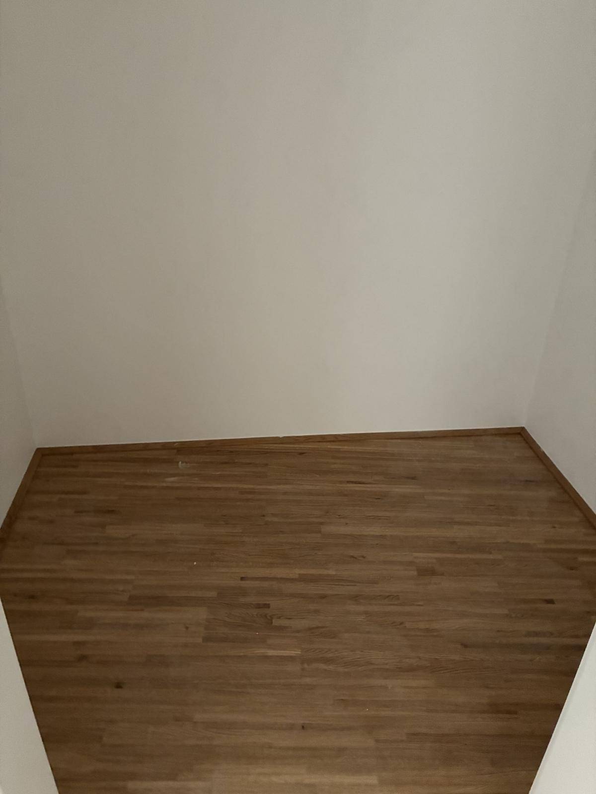 Kleiner Abstellraum mit Holzboden, ideal für zusätzlichen Stauraum und Haushaltsgeräte.