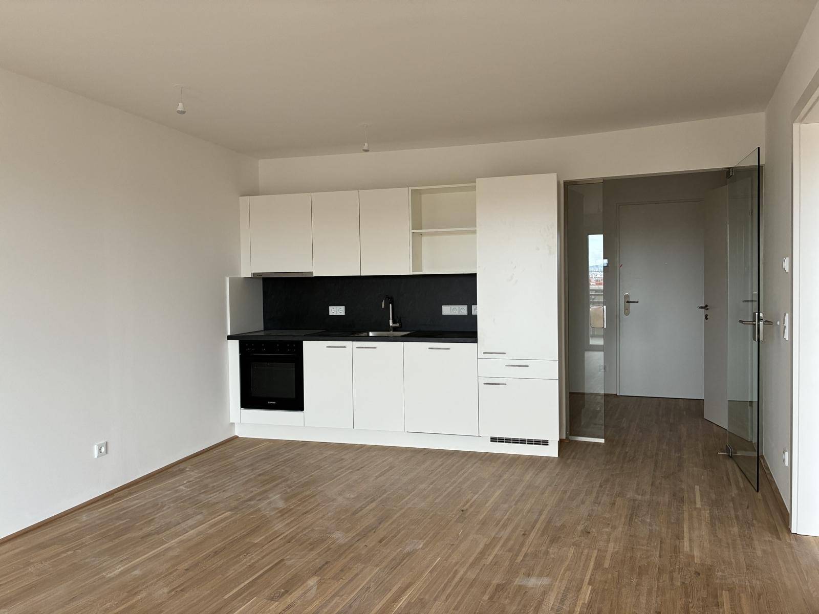 Funktionale Einbauküche mit weißen Fronten und integriertem Backofen, Teil eines offenen Wohnkonzepts.