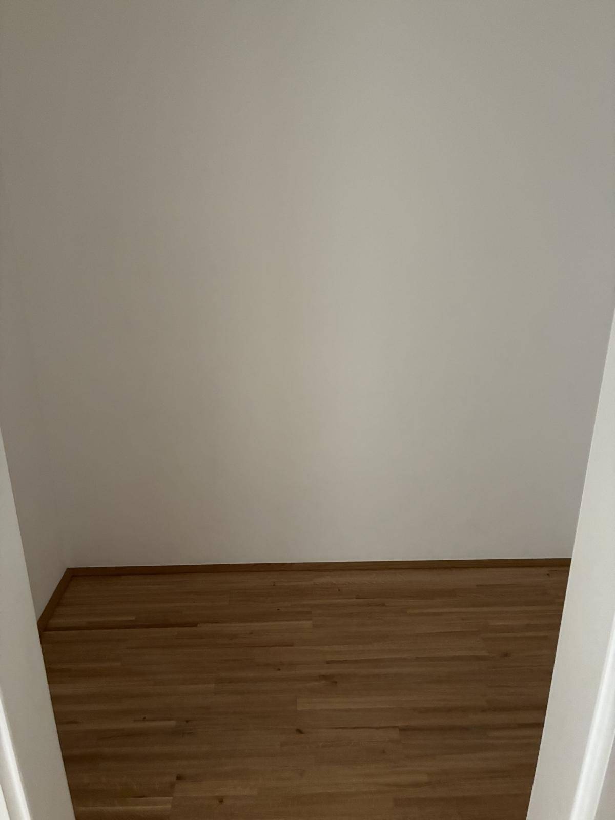 Kleiner, leerer Raum mit Holzboden, möglicherweise ein Abstellraum oder begehbarer Schrank.