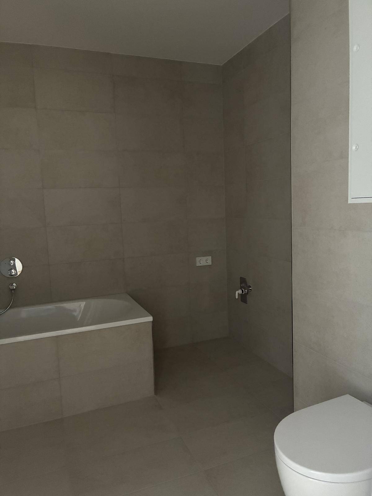 Modernes Badezimmer mit beigefarbenen Fliesen und einer eingebauten Badewanne.