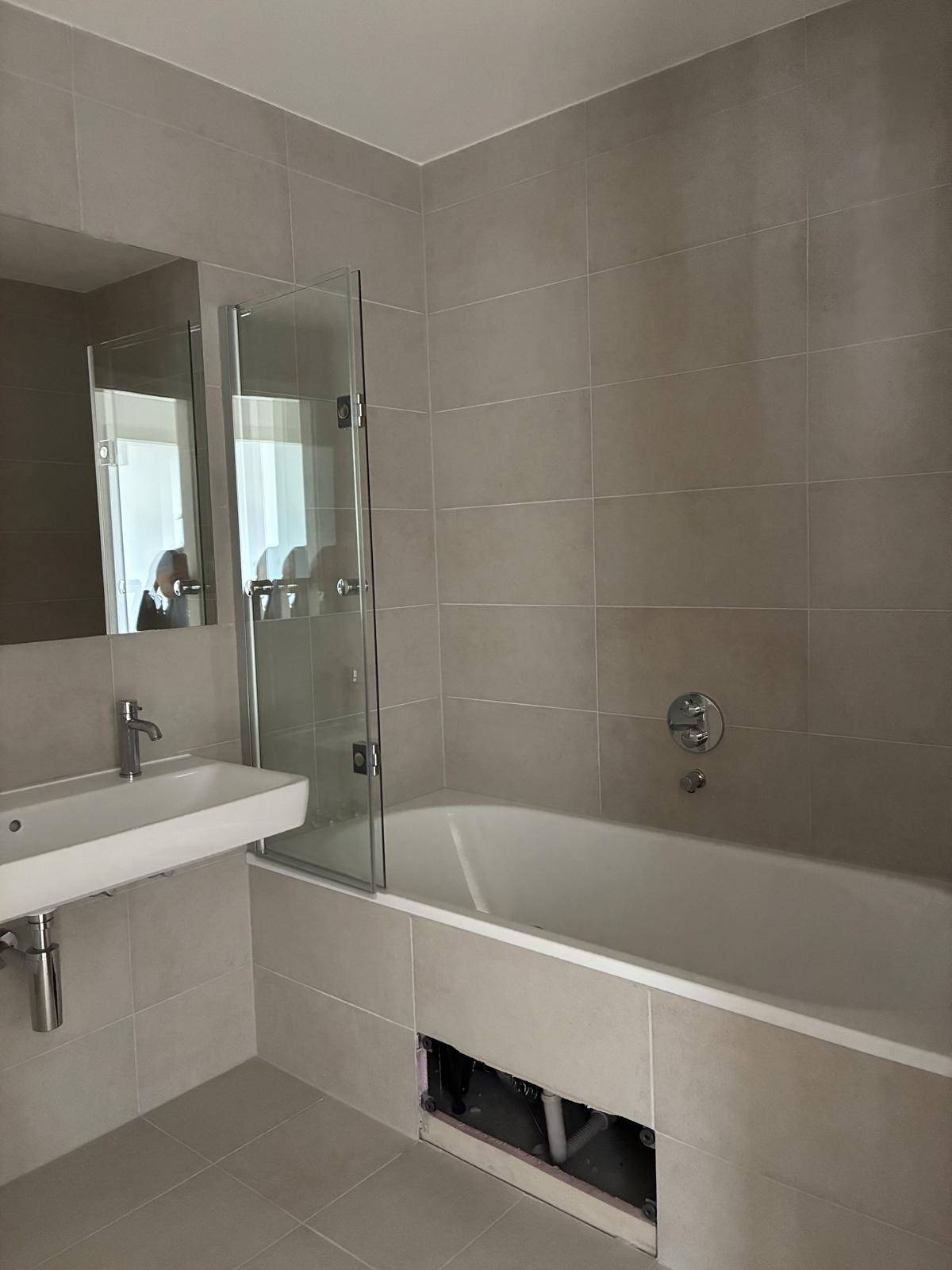 Modernes Badezimmer mit Badewanne und Waschbecken, ausgestattet mit hellgrauen Fliesen.