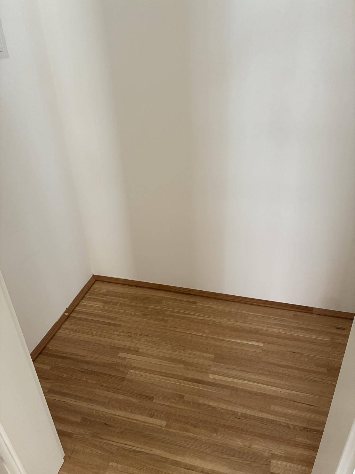 Kleiner Abstellraum mit Holzboden und weißen Wänden, ideal für zusätzlichen Stauraum.