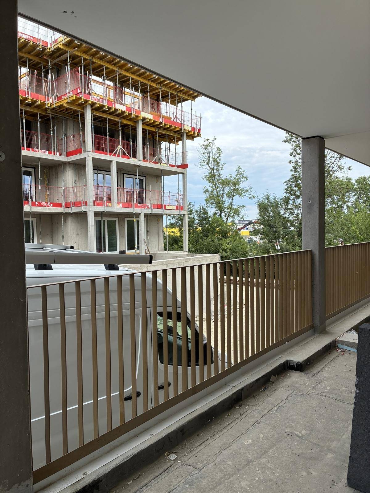 Balkon mit modernem Metallgeländer und Blick auf die umliegende Baustelle und neue Gebäude.