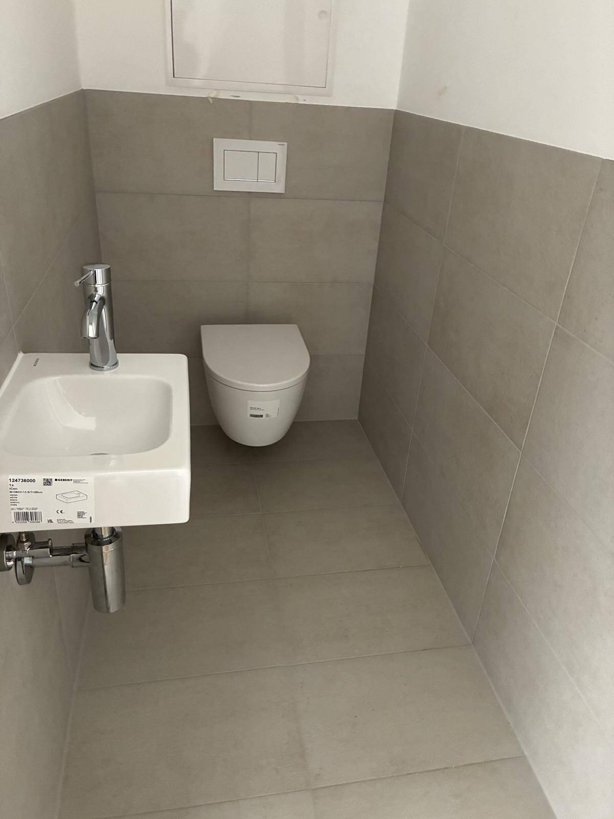 Kleines Gäste-WC mit modernem Waschbecken und Wand-WC in neutralen Farben.