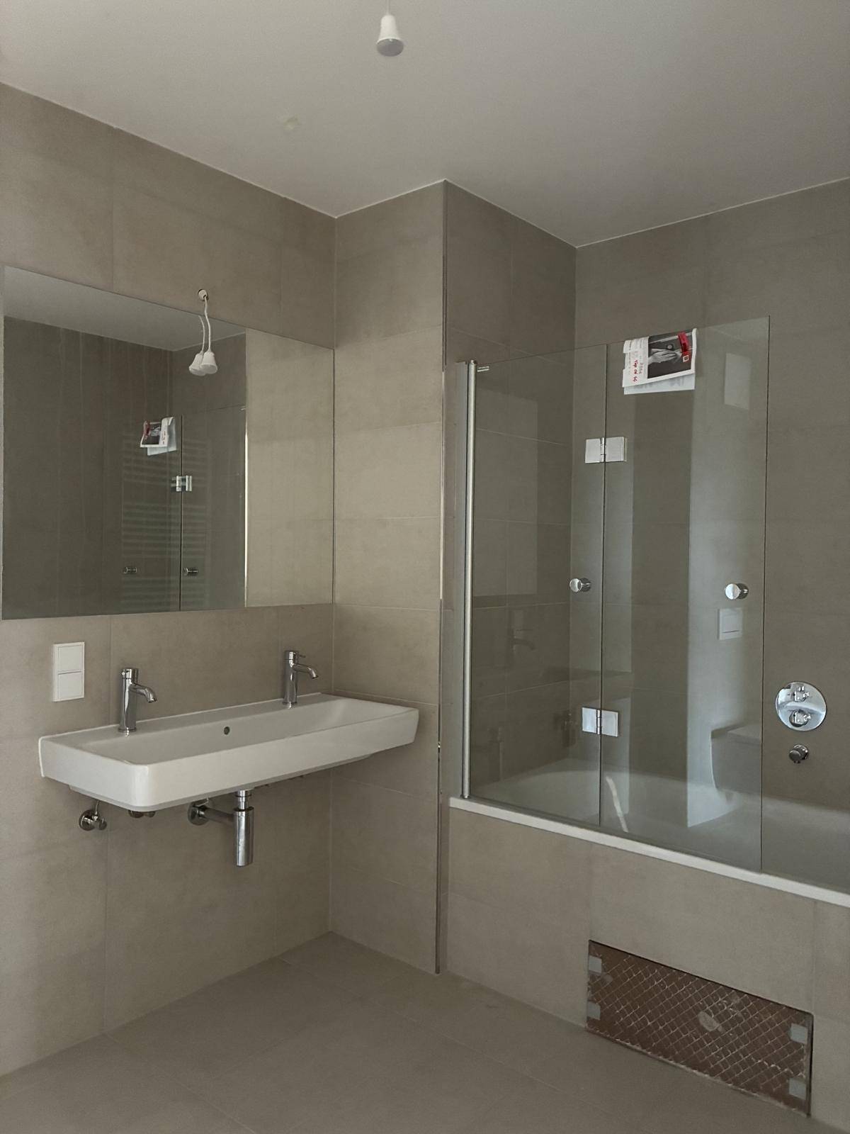 Modernes Badezimmer mit Badewanne, doppelten Waschbecken und großen Fliesen.