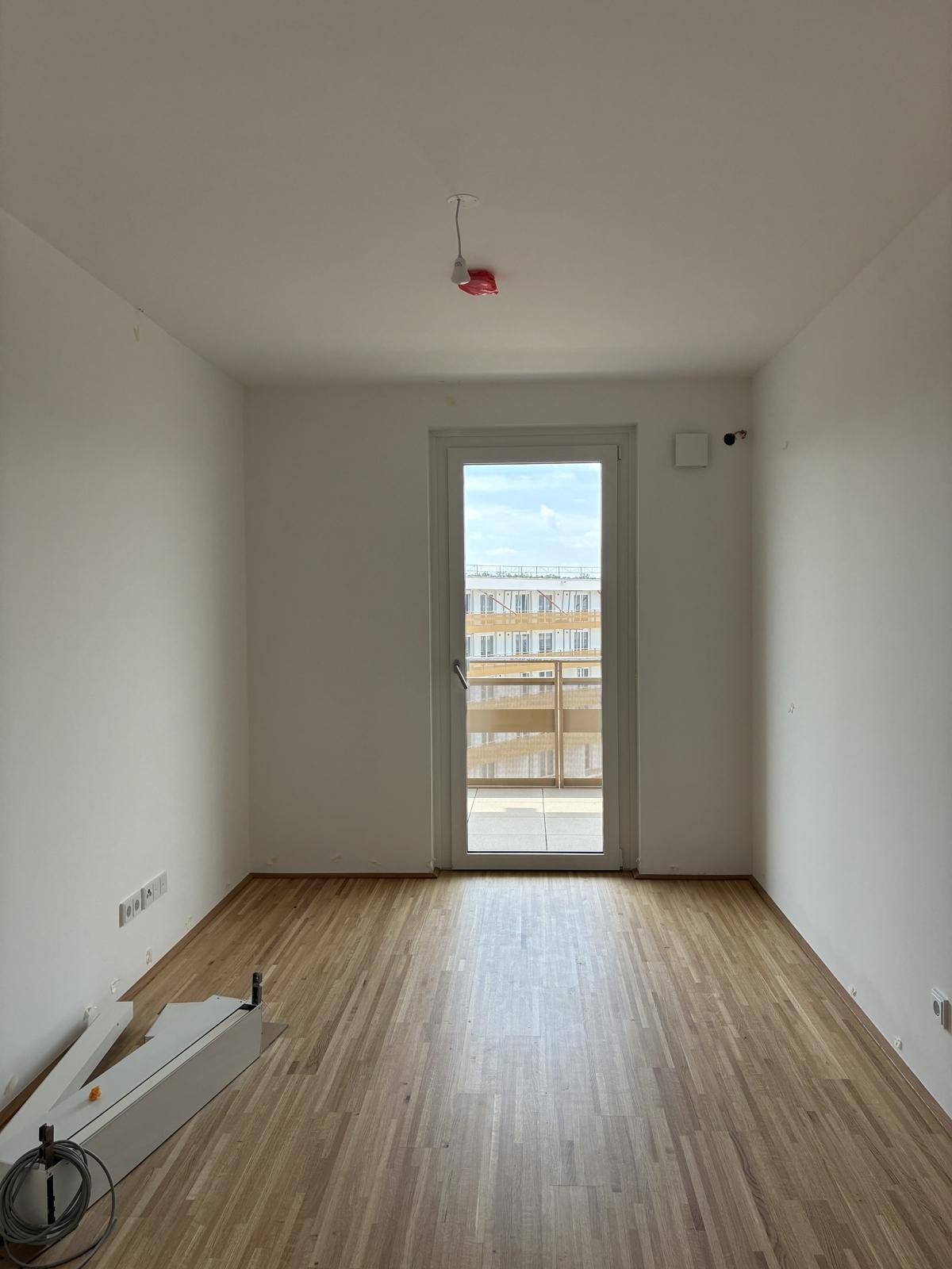 Helles Zimmer mit Holzboden und Balkontür, bereit für die individuelle Einrichtung.