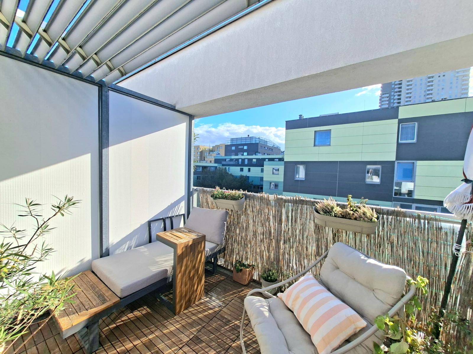 Sonniger Balkon mit Liegestuhl, Pflanzen und Holzboden, ideal zum Entspannen im Freien.