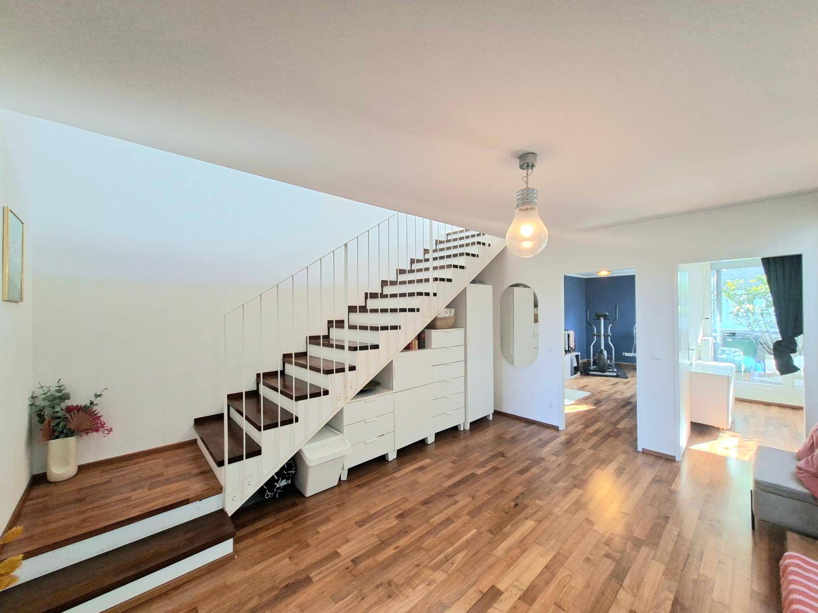 Heller Wohnbereich mit Holzboden und einer modernen Treppe mit integriertem Stauraum.