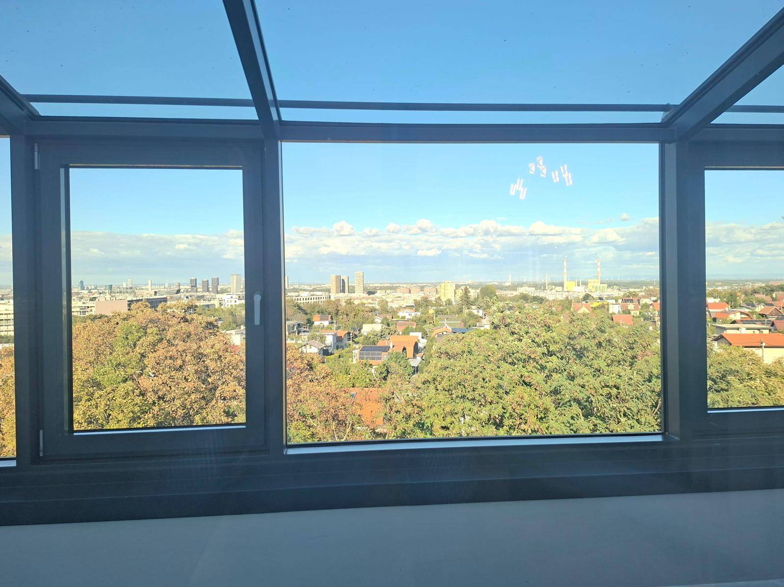Raum mit Panoramafenstern und Glasdach, der einen weiten Blick über die Stadt und die Umgebung bietet.