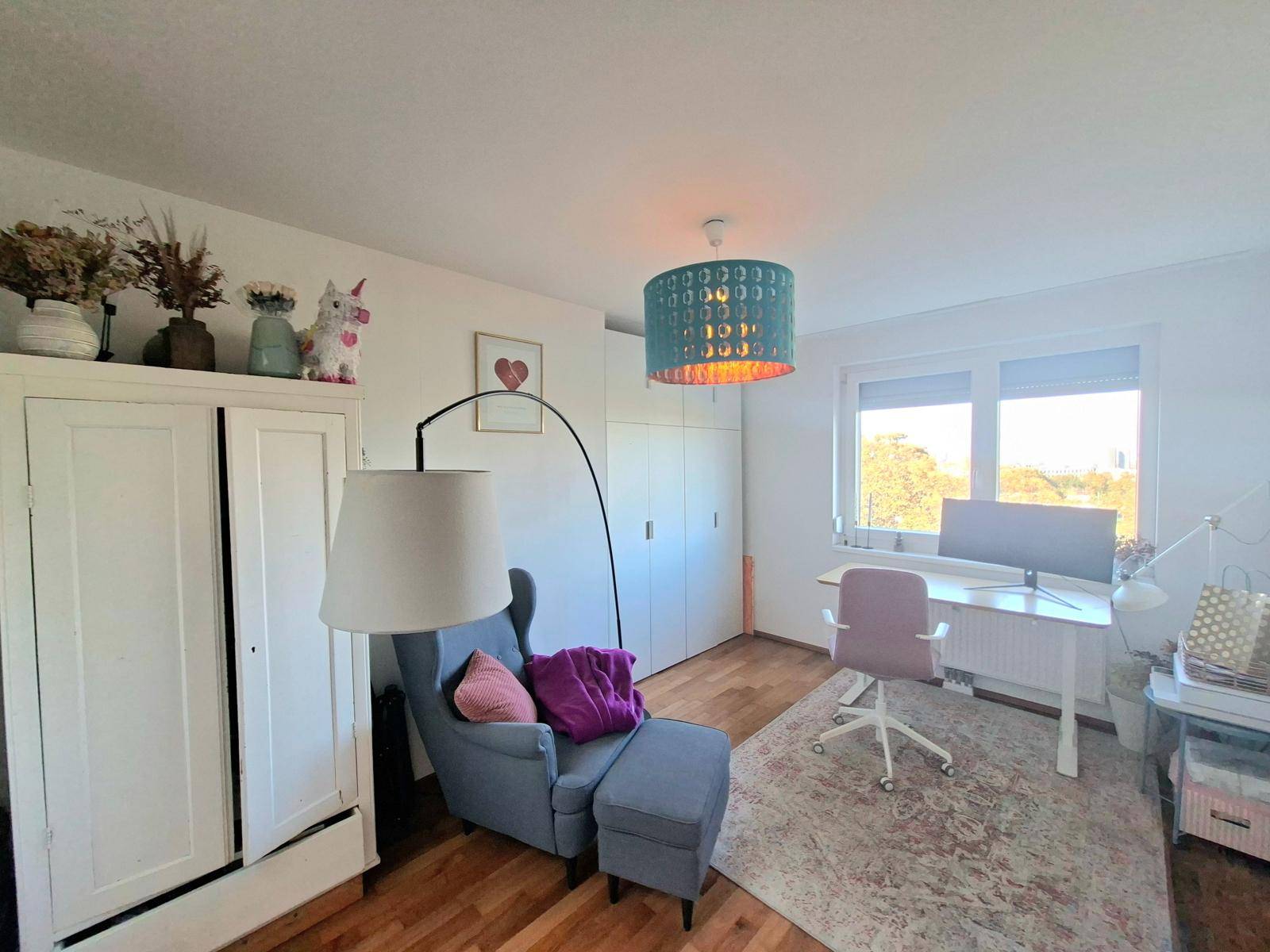 Helles Arbeitszimmer mit Schreibtisch, bequemen Sessel und integrierten Schränken für Stauraum.
