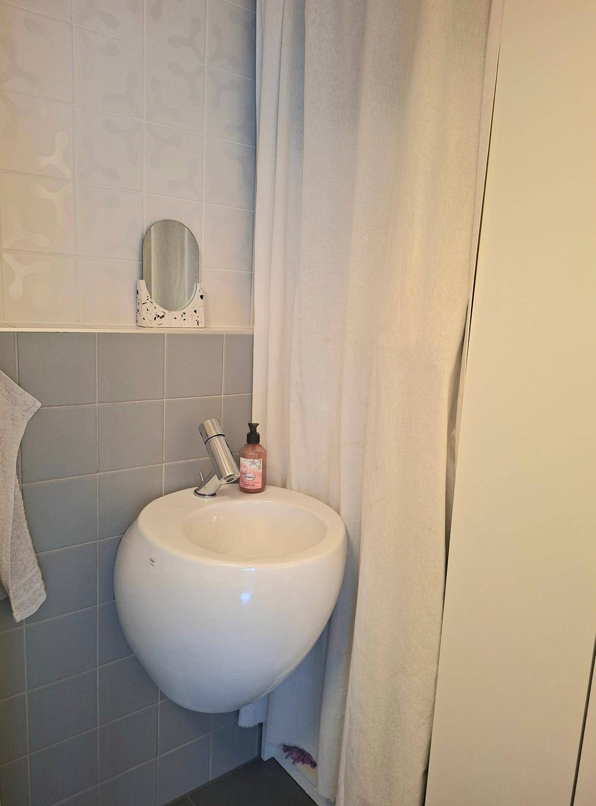 Kleines Waschbecken im Gäste-WC mit modernen Armaturen und grauen Fliesen.