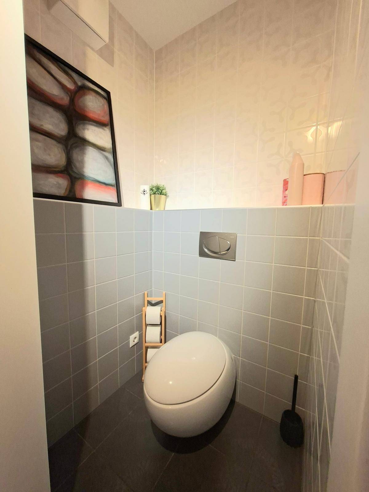 Modernes Gäste-WC mit Wand-WC und grauen Fliesen, minimalistisch gestaltet.