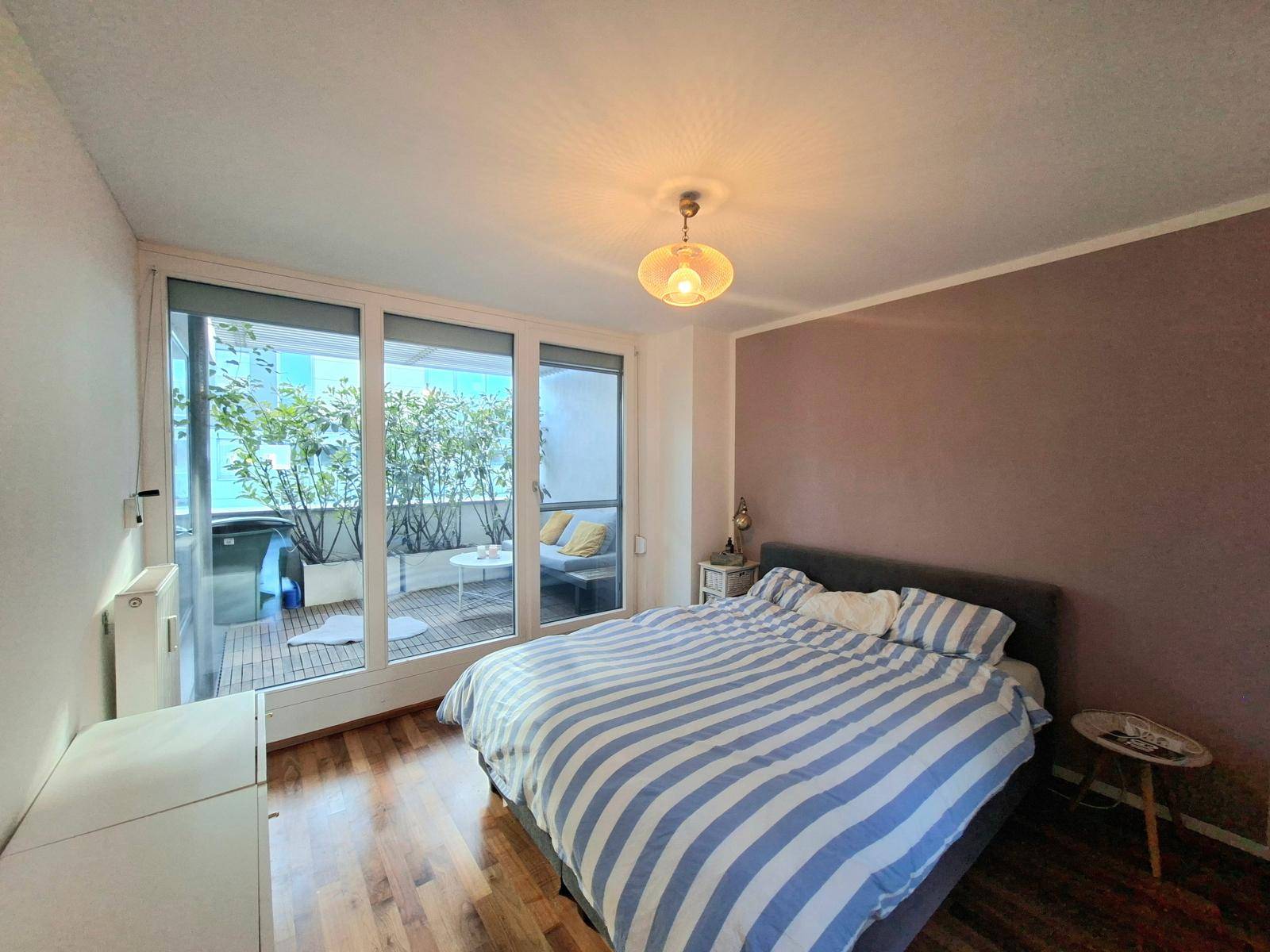 Schlafzimmer mit Doppelbett, Holzboden und Zugang zu einem privaten Außenbereich.