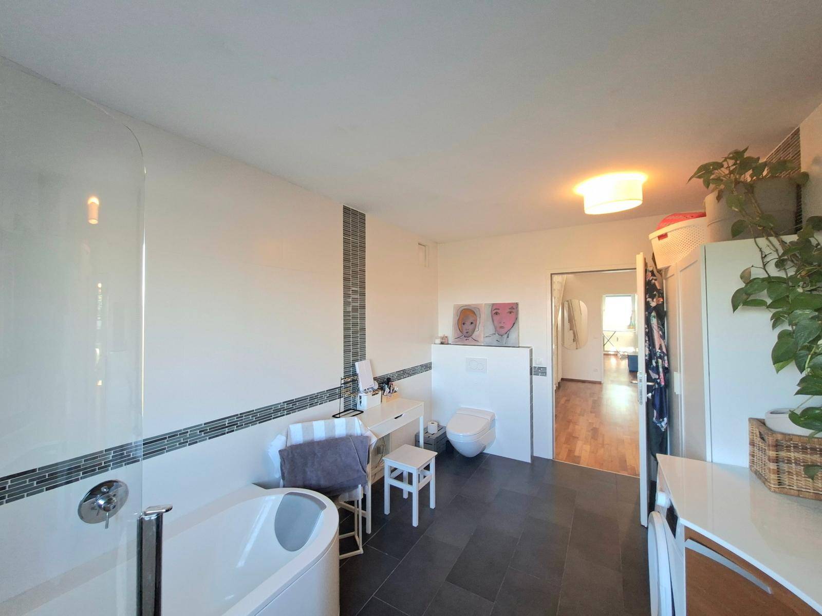 Modernes Badezimmer mit Dusche, wandhängendem WC und stilvollen Fliesenakzenten an der Wand.