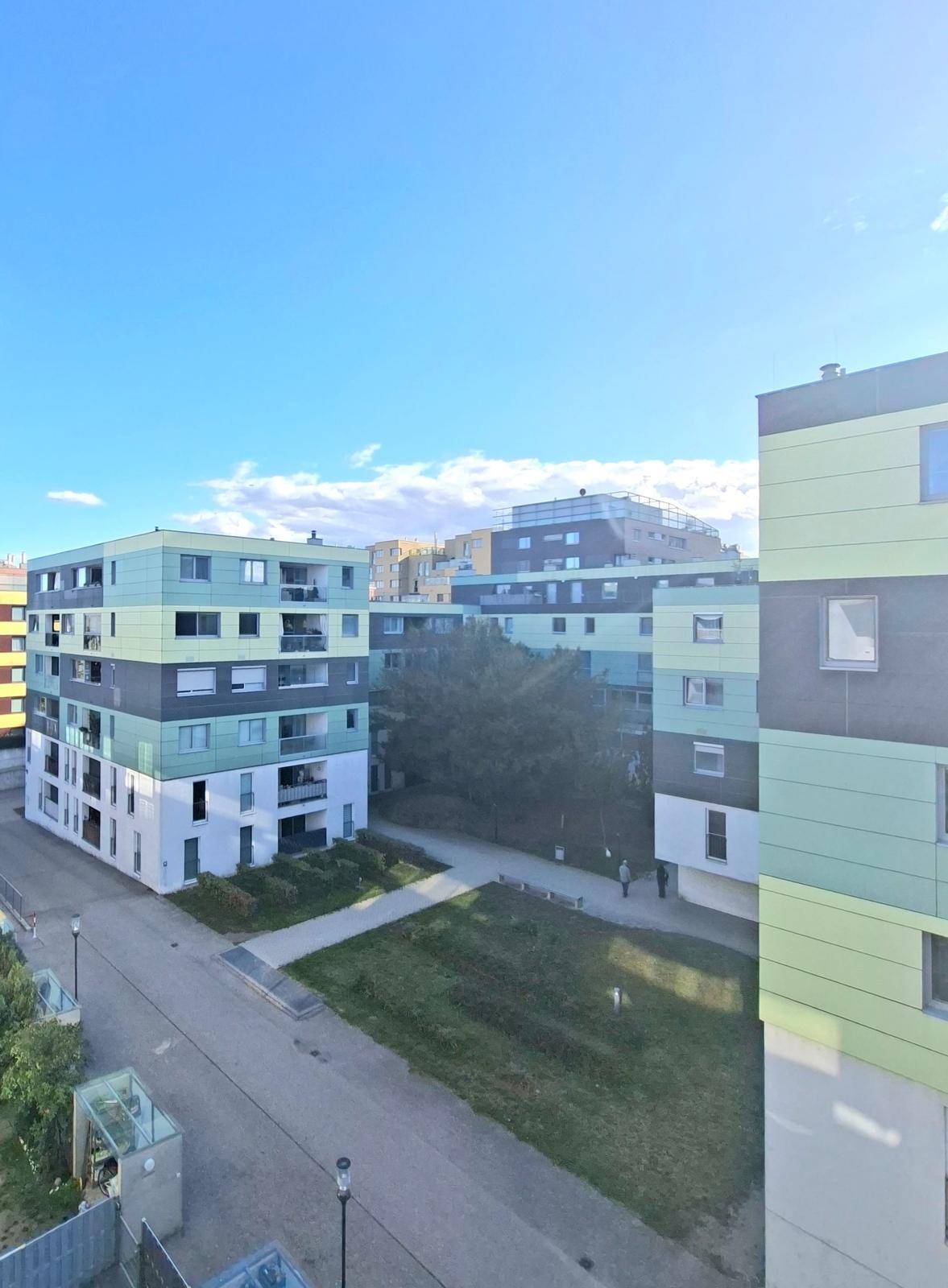 Blick auf moderne Wohngebäude mit farbigen Fassaden und Grünflächen in der Umgebung.