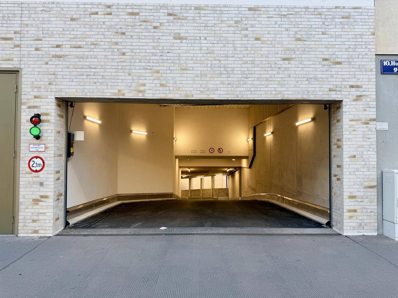 Einfahrt zu einer Tiefgarage mit Rampe, Ampelsystem und Höhenbegrenzung.