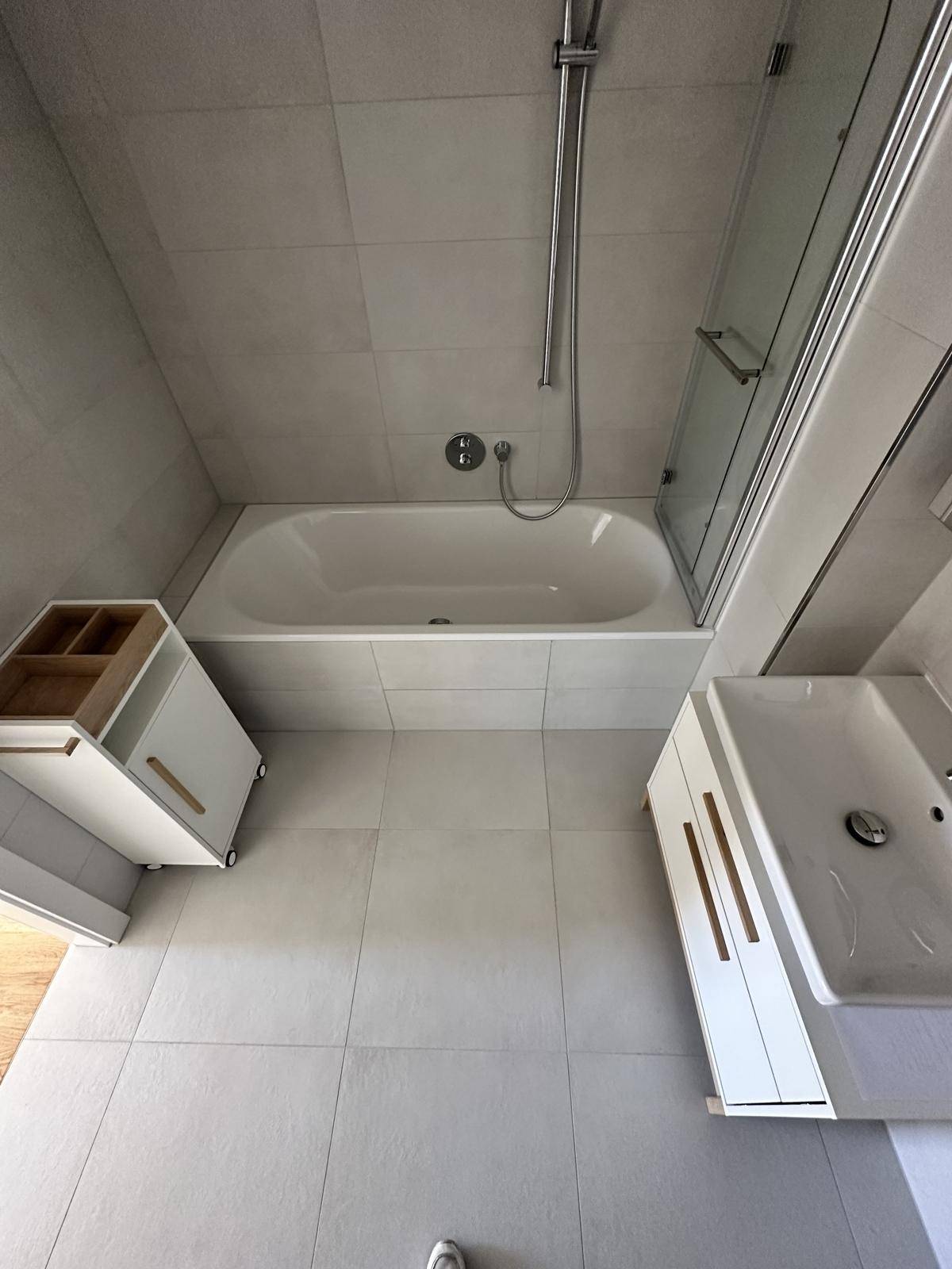 Modernes Badezimmer mit Badewanne und Duschabtrennung, hell gefliest und pflegeleicht.