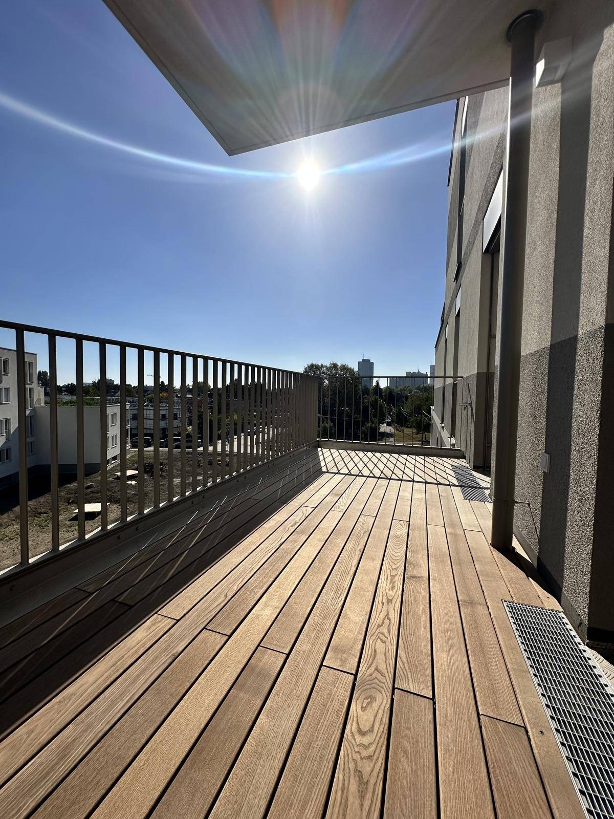 Sonnige Loggia mit Holzboden und Blick auf die Umgebung, perfekt für entspannte Stunden.