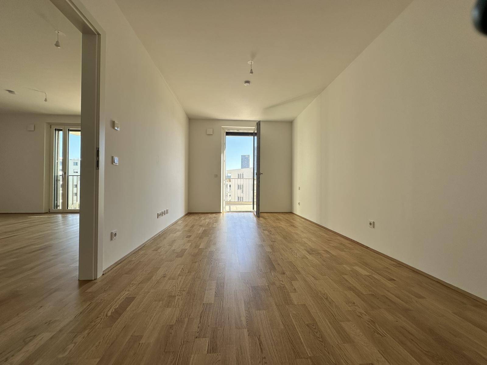 Geräumiges Wohnzimmer mit Parkettboden und Balkonzugang, ideal für helle Einrichtung.