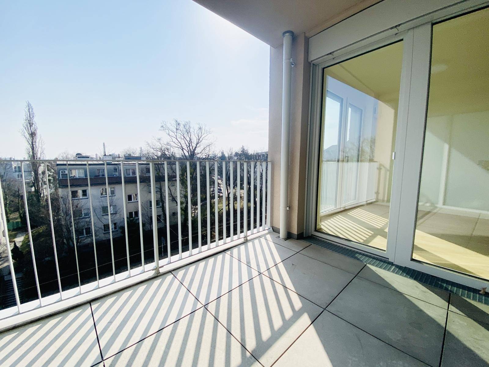 Sonniger Balkon mit Fliesenboden und Blick auf die umliegende Wohngegend.