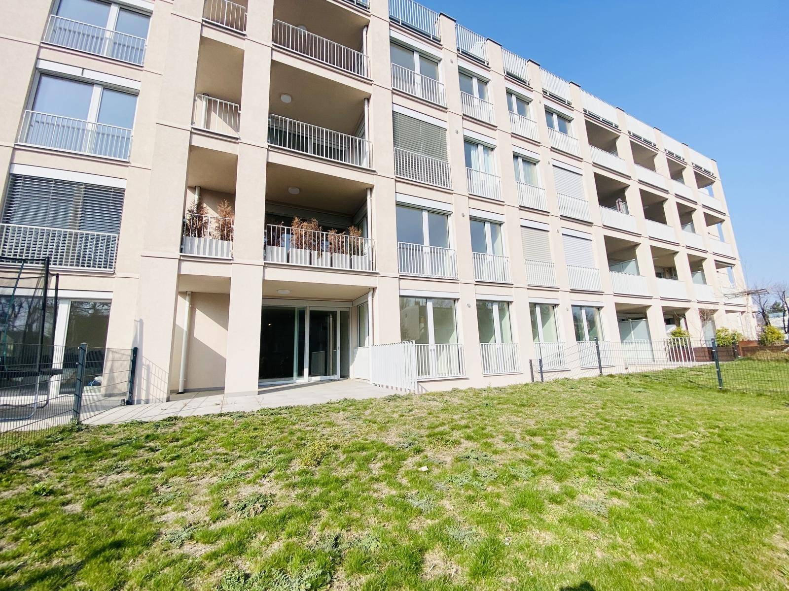 Moderne Wohnanlage mit mehreren Balkonen, großen Fenstern und gepflegter Rasenfläche.
