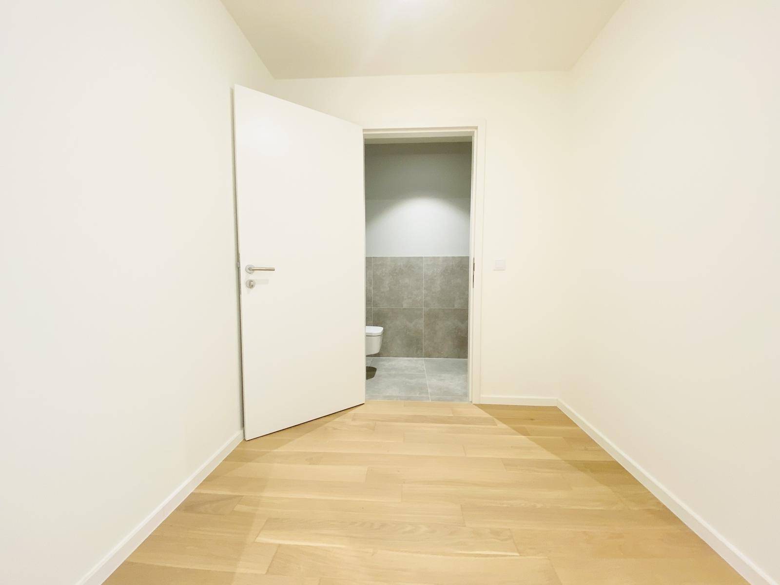 Kleiner Raum mit Parkettboden und Zugang zu einem gefliesten WC.