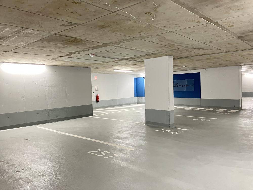 Weitläufige Tiefgarage mit vielen freien Parkplätzen und farbigen Akzenten an den Wänden.