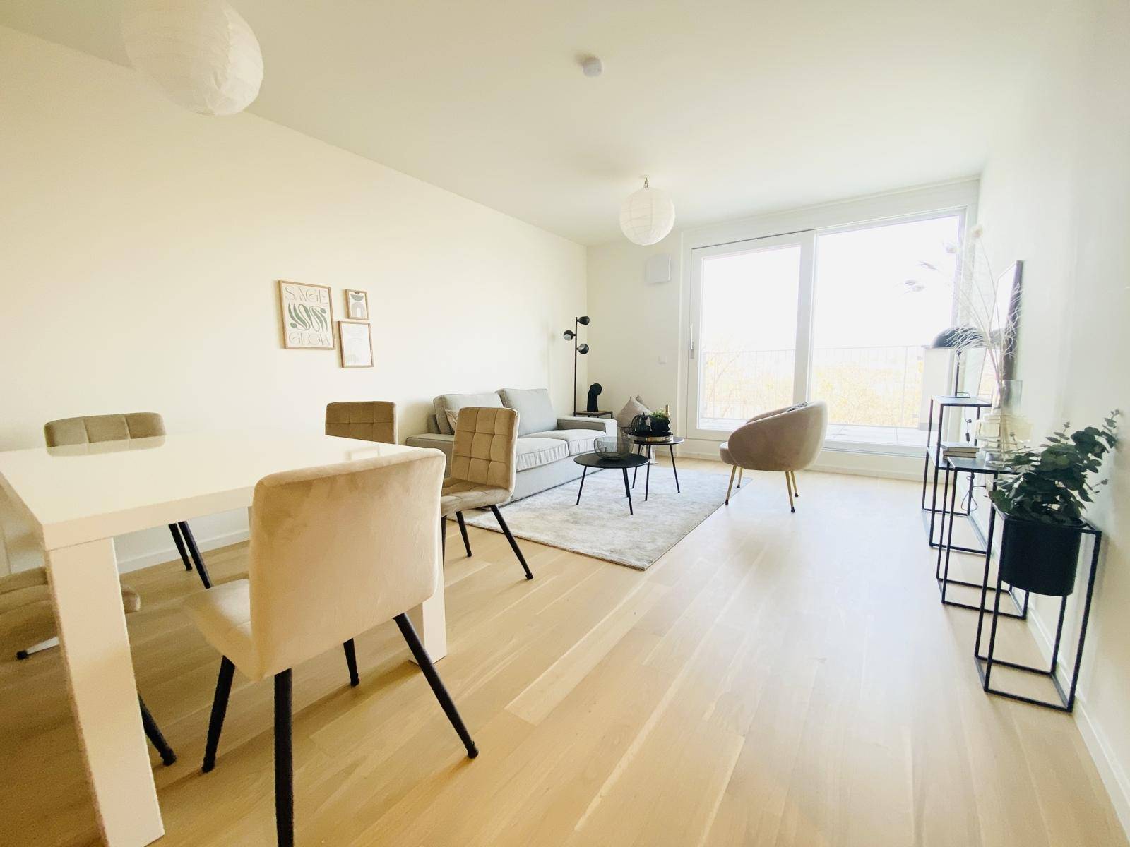 Offener Wohn-Essbereich mit großen Fenstern, Holzboden und moderner Einrichtung, ideal für geselliges Beisammensein.