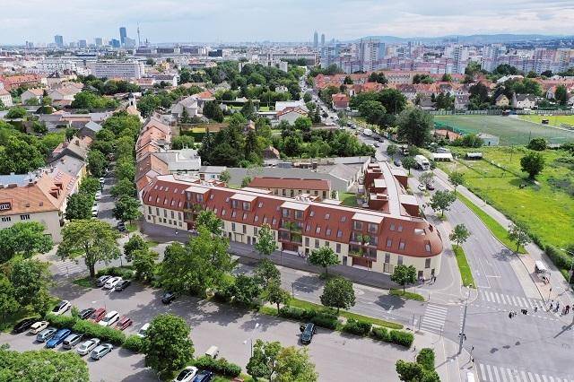 Luftaufnahme des Wohnkomplexes mit rotem Dach und der umliegenden städtischen Landschaft.