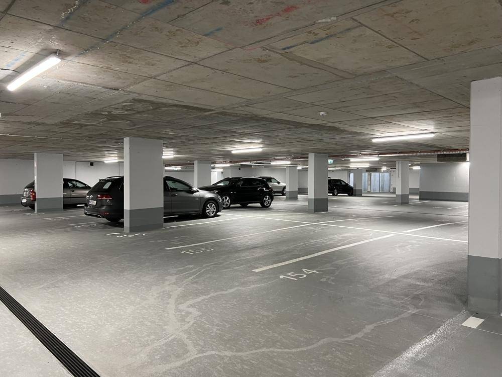 Geräumige Tiefgarage mit markierten Parkplätzen und mehreren geparkten Fahrzeugen.