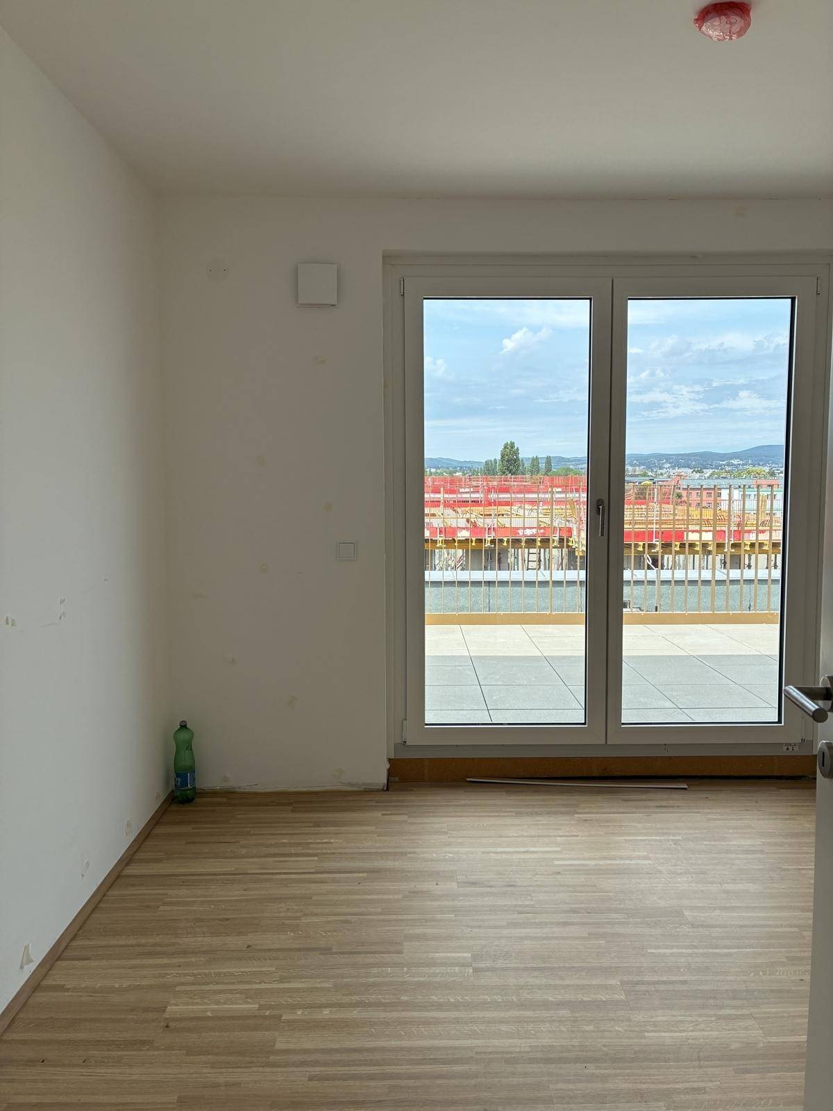 Helles Schlafzimmer mit Holzboden und Zugang zu einem Balkon mit Blick auf die Umgebung.