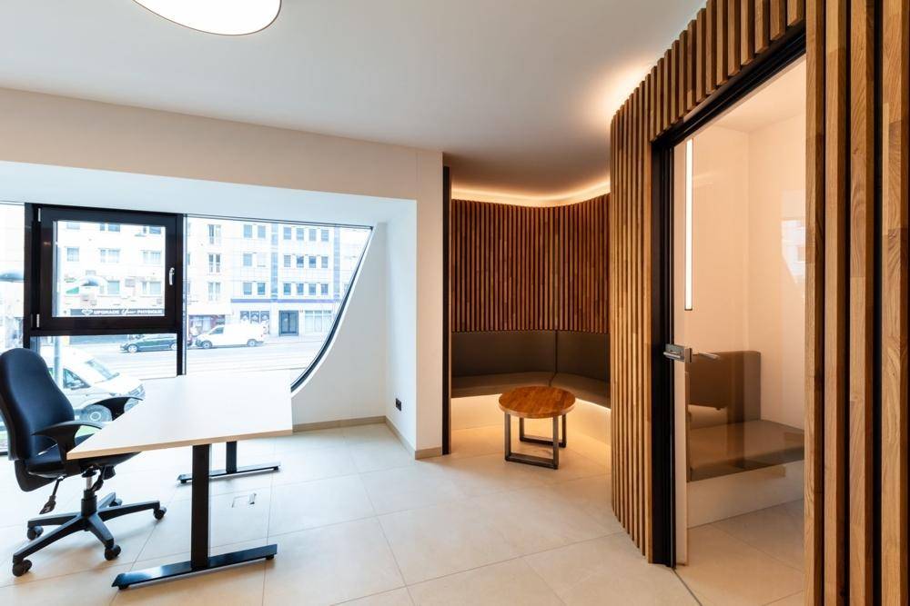 Moderner Bürobereich mit Arbeitsplätzen und einer gemütlichen Sitzecke mit Holzvertäfelung.