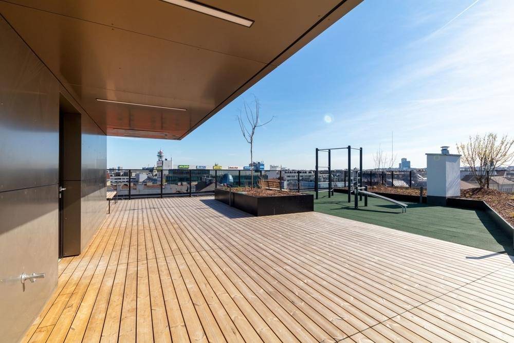 Großzügige Dachterrasse mit Holzdeck, Fitnessgeräten und weitem Blick über die Stadt.