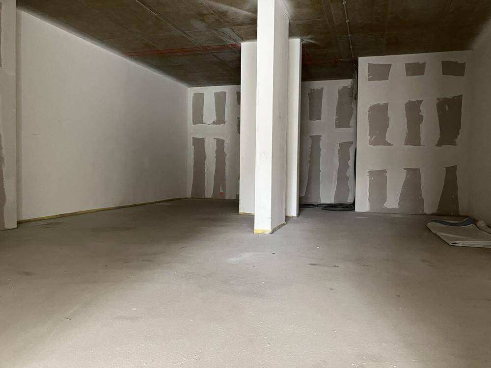 Weitläufiger Rohbau mit Betonboden und Säulen, ideal für flexible Raumgestaltung.