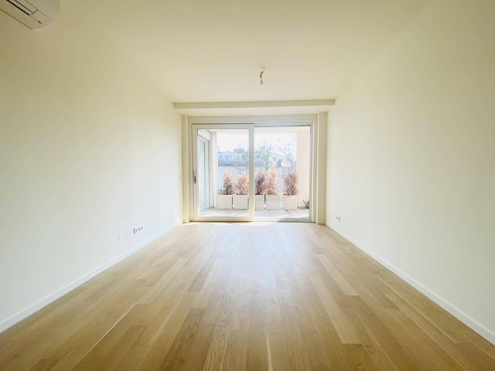 Geräumiges Zimmer mit Parkettboden und Schiebetür zu einer Terrasse.