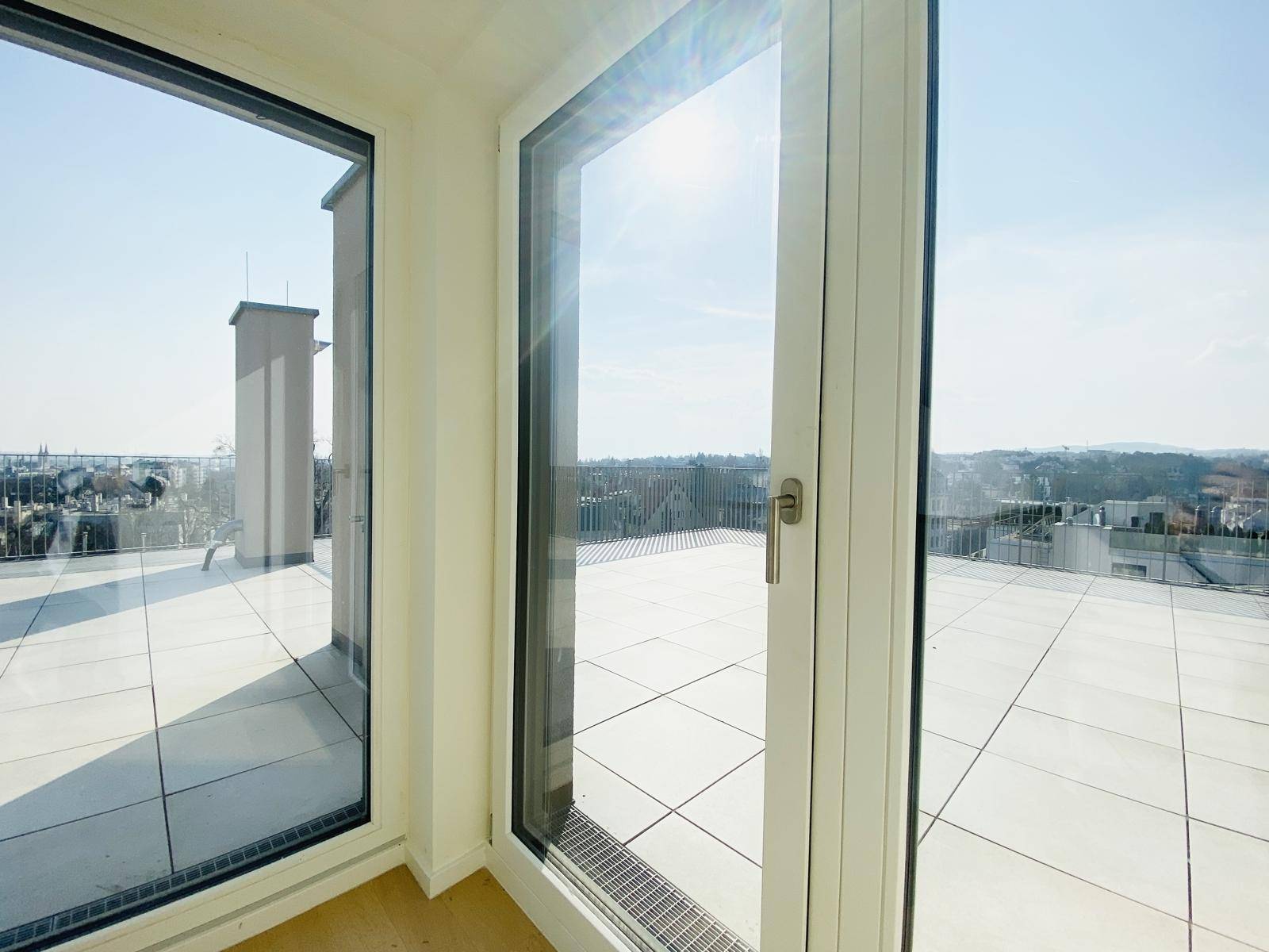 Große Glasfront mit Zugang zur Dachterrasse, die viel Tageslicht in den Innenraum lässt.