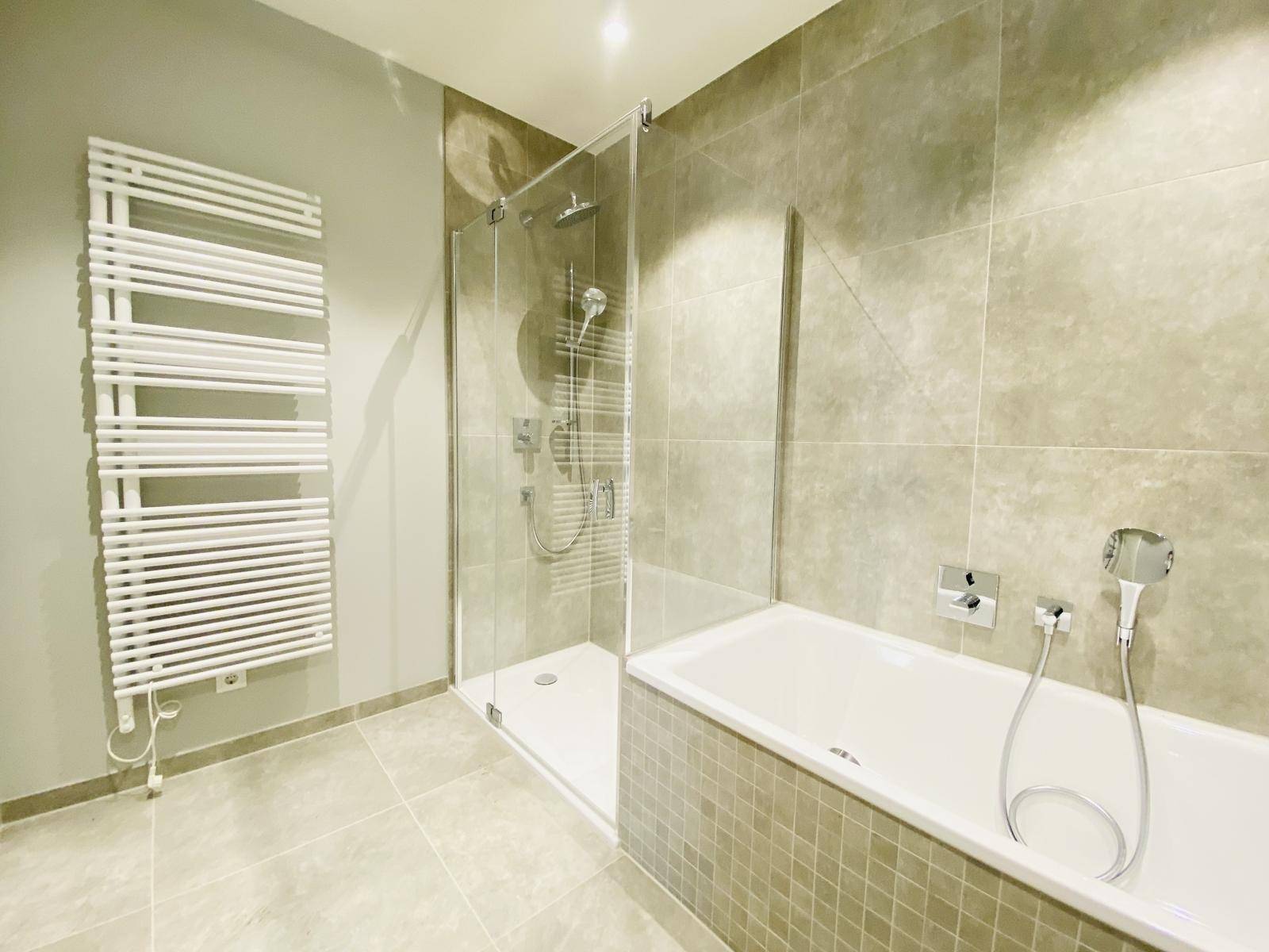 Modernes Badezimmer mit Badewanne, Duschkabine und beheiztem Handtuchhalter.