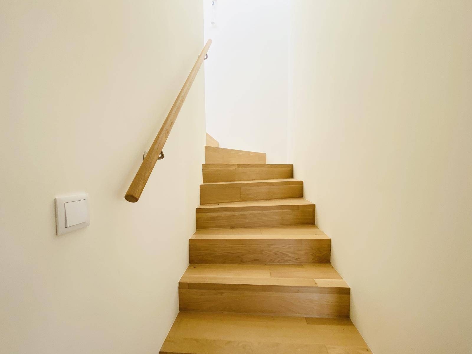 Elegante Holztreppe mit schlichtem Geländer, die verschiedene Ebenen des Hauses verbindet.