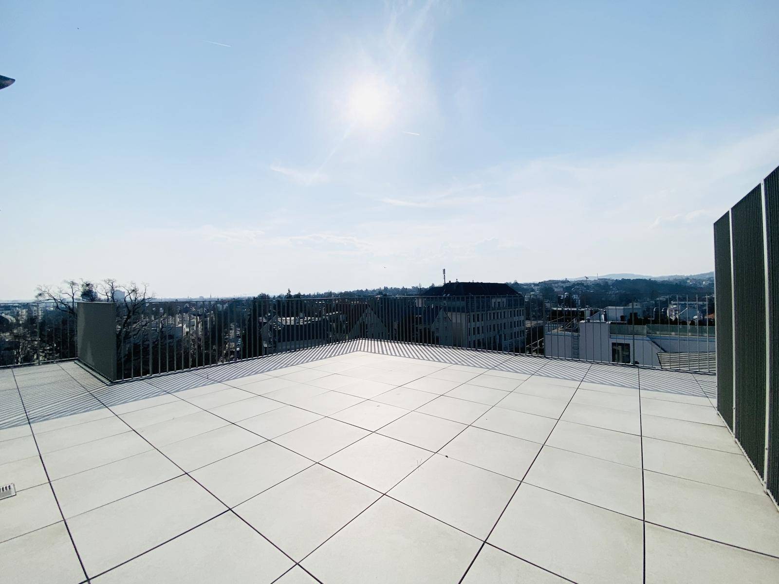 Weitläufige Dachterrasse mit Fliesenboden und Panoramablick über die Stadt und die Umgebung.