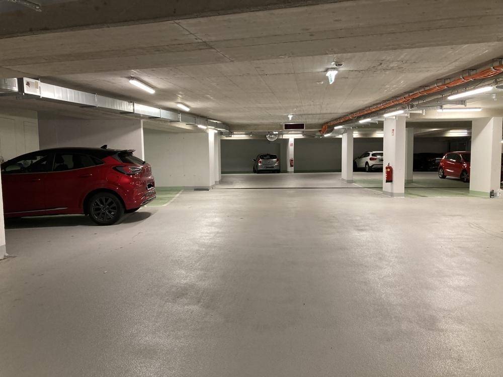 Weitläufige Tiefgarage mit vielen Stellplätzen, Säulen und guter Beleuchtung.