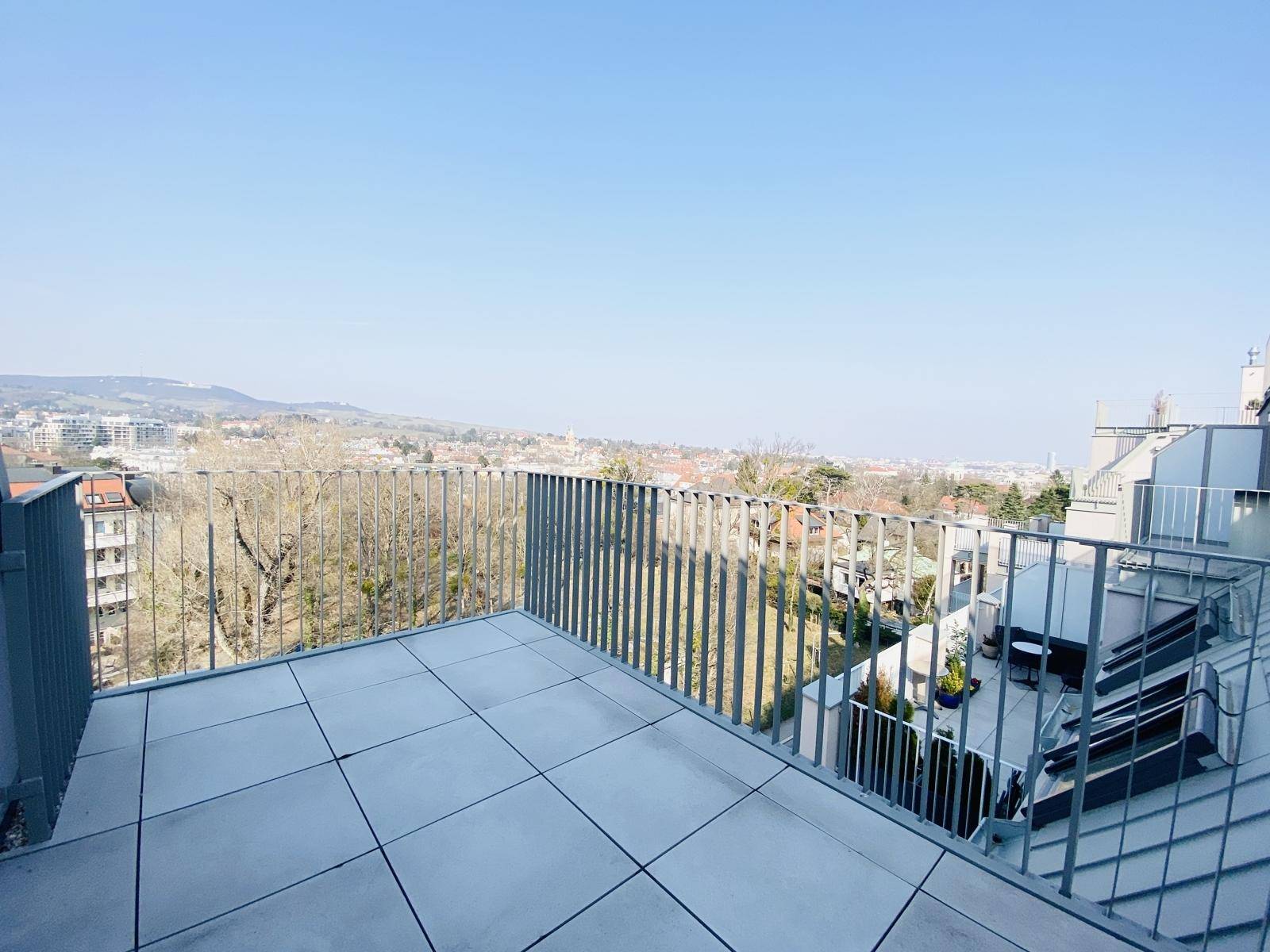Große Dachterrasse mit Fliesenboden und weitem Blick über die Stadt und die Hügel.