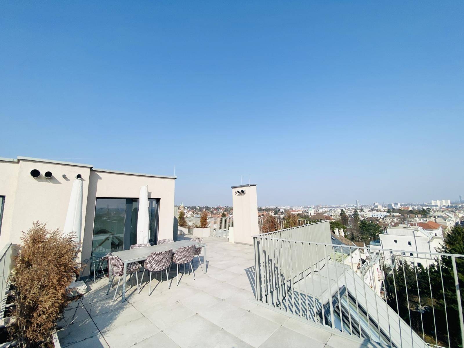 Weitläufige Dachterrasse mit Blick auf die moderne Architektur des Gebäudes und die Stadt.