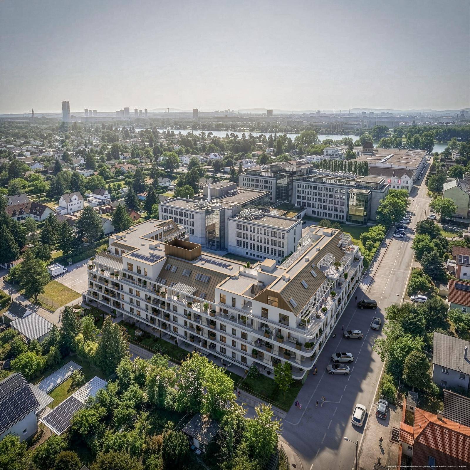 Luftaufnahme der modernen Wohnanlage in einer grünen Umgebung mit Blick auf die Stadt und einen See.