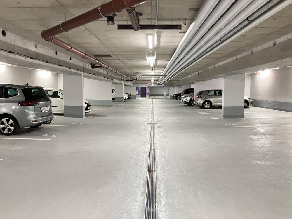 Lange Reihe von Parkplätzen in der Tiefgarage mit sauberem Boden und guter Beleuchtung.