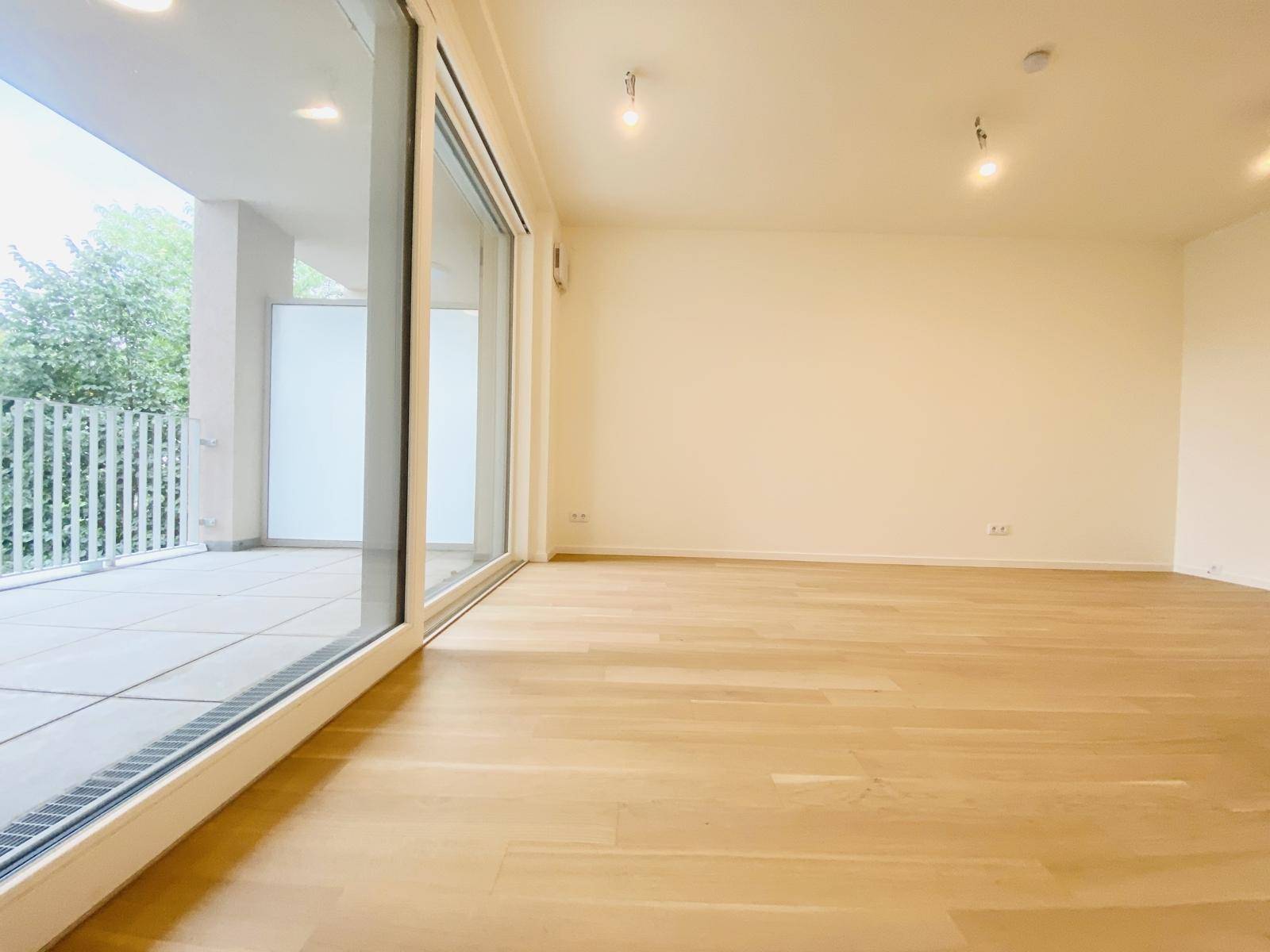 Lichtdurchfluteter Wohnbereich mit Parkettboden und großzügigem Zugang zum Balkon.
