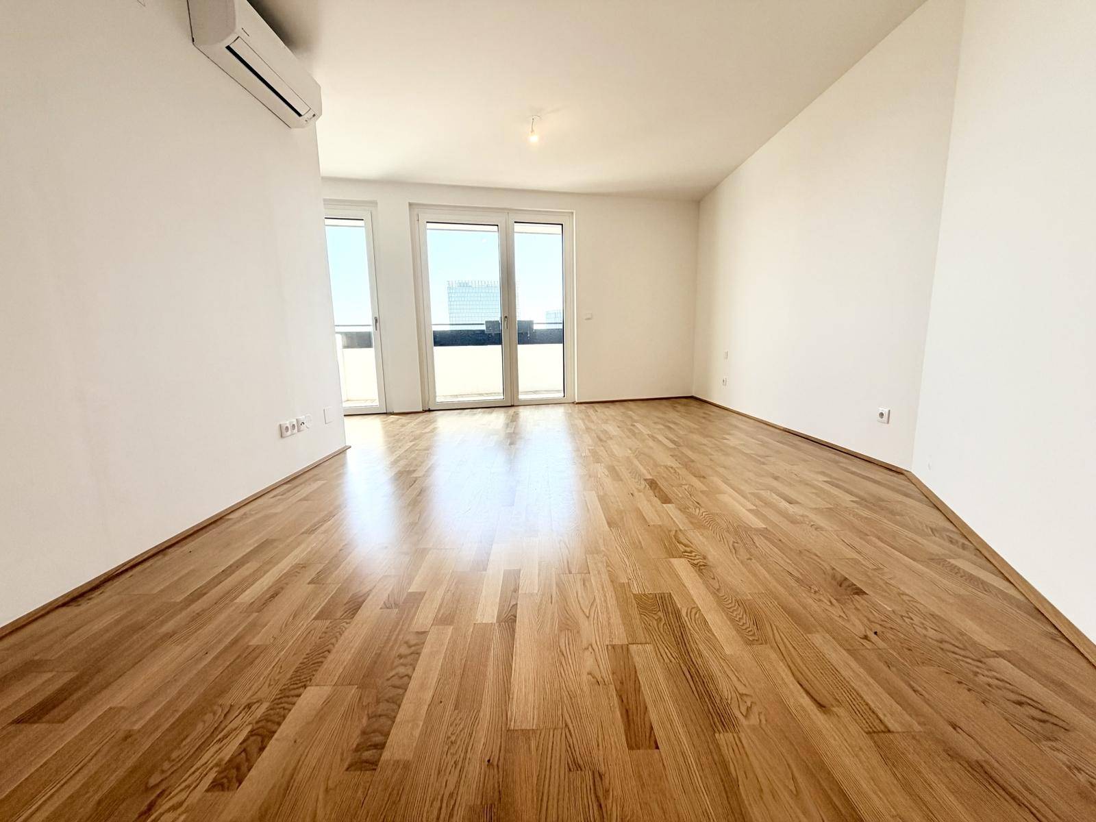 Geräumiger, heller Raum mit Holzboden und Klimaanlage, ideal für Wohnzwecke.