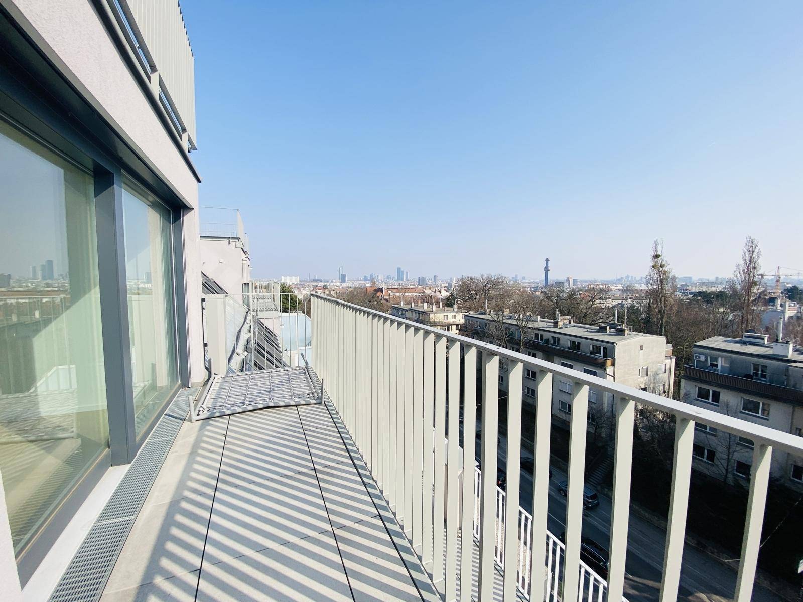 Langer Balkon mit Stadtblick und moderner Metallbrüstung, ideal für Entspannung im Freien.