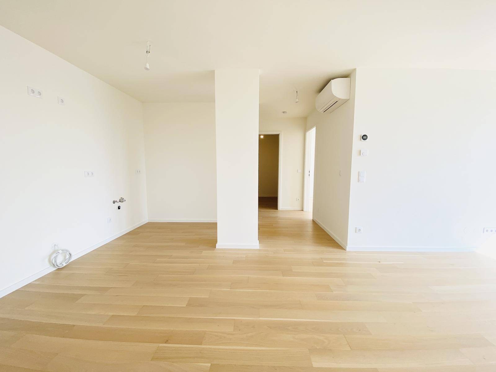Weitläufiger Wohnbereich mit hellem Parkettboden und moderner Klimaanlage.