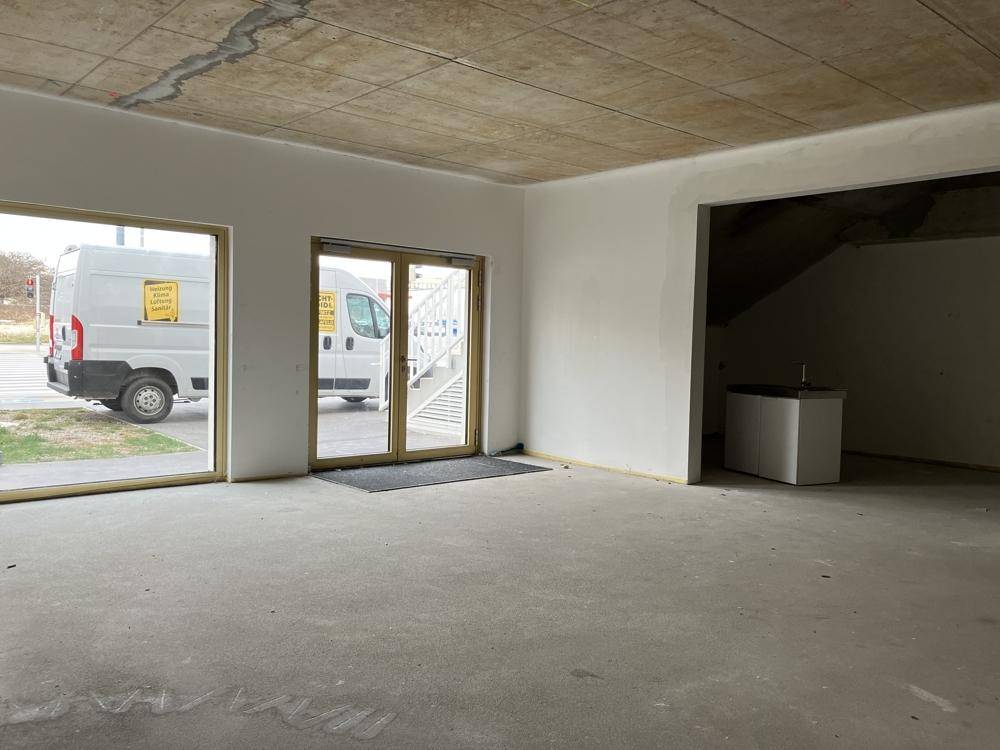 Unfertiger Gewerberaum mit großen Fenstern und Blick auf die Straße, bereit für den Ausbau.
