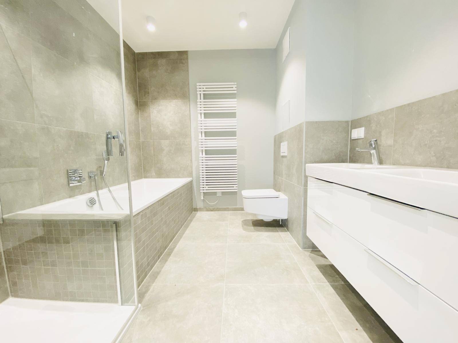 Geräumiges Badezimmer mit Badewanne, Dusche, WC und beheiztem Handtuchhalter.